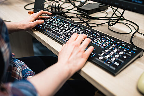 Zwei Hände auf einer Tastatur mit größeren, weißen Buchstaben. 